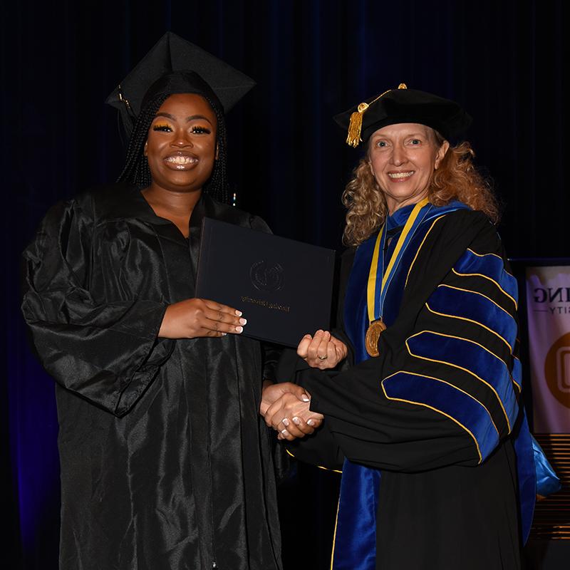 Herzing graduat receives her diploma from Renee Herzing.